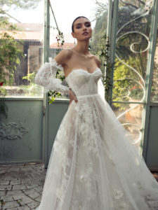 Woman in greenhouse. hands on hips to showcase her detachable voluminous sleeves that compliment her soft corset a line bridal gown