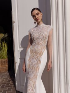 high neckline glamorous detailed wedding gown with crepe material on the sides of the gown. Gown hugs the hour glass figure of the bride